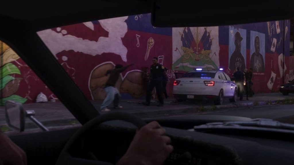 Bir arabanın içinden direksiyon başından dışarıdaki grafitili duvar önünde gerçekleşen polis müdahalesine bakış