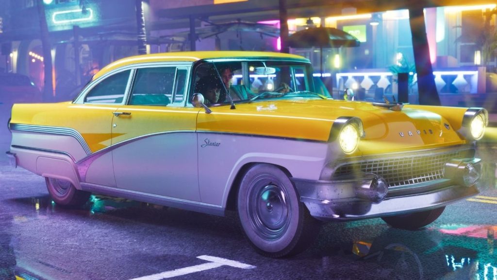 Gece neon ışıklı Vice City caddesinde ıslak zeminde farları açık şekilde duran, üstü sarı altı beyaz renkli iki kapılı klasik Vapid Stanier otomobil